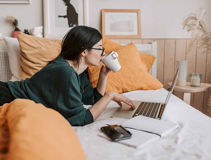 Imagen de mujer bebiendo café y estudiante frente a su computador.