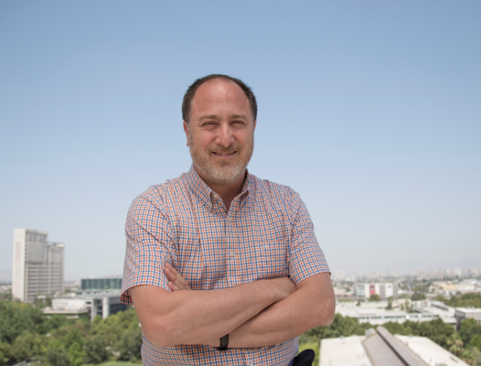 Roberto González, psicólogo UC, en la terraza del Centro de Innovación UC, y de fondo, el campus San Joaquín.