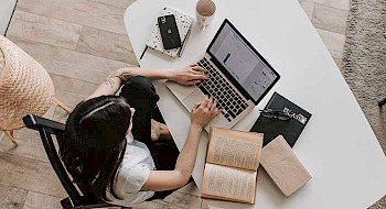 Imagen cenital de mujer escribiendo en su computador.