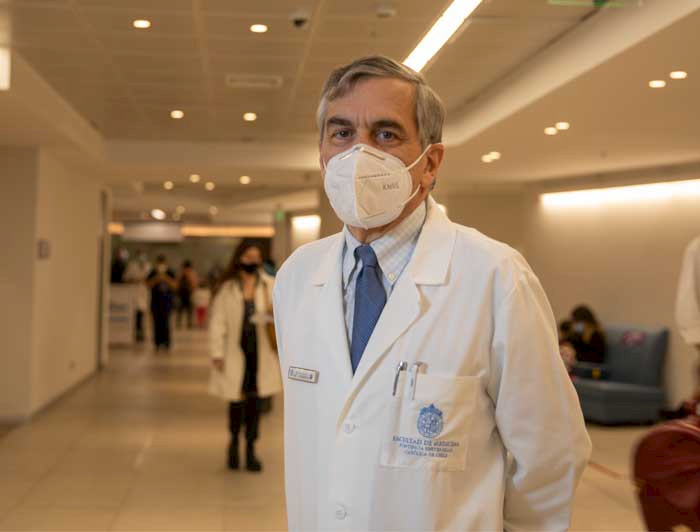 El decano de Medicina, Felipe Heusser, con bata blanca y mascarilla en un pasillo del hospital de calle Marcoleta.