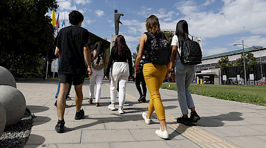 Imagen de las espaldas de un grupo de estudiantes en campus San Joaquín que sale del Centro de Innovación en un día soleado.