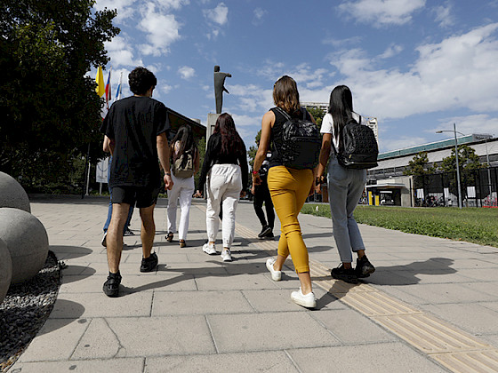 Imagen de las espaldas de un grupo de estudiantes en campus San Joaquín que sale del Centro de Innovación en un día soleado.