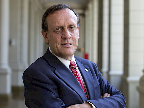 President Ignacio Sanchez in a suit and tie standing with his arms crossed