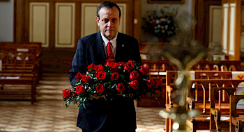 hombre dentro de una capilla llevando ramo de rosas rojas