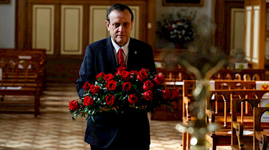 hombre dentro de una capilla llevando ramo de rosas rojas