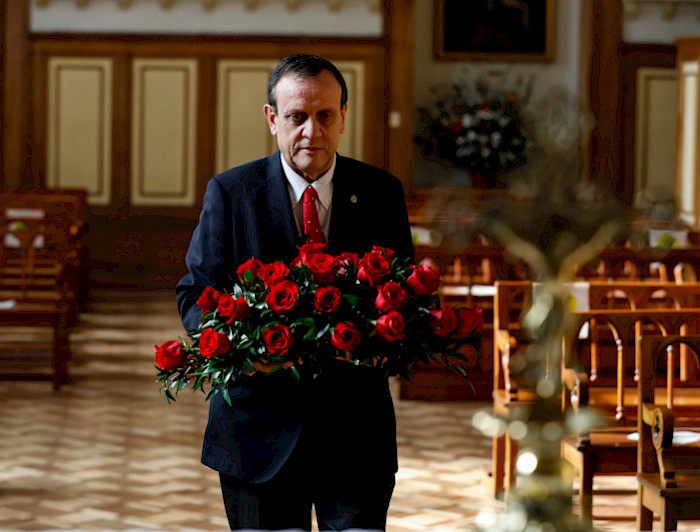 hombre dentro de una capilla llevando ramo de rosas rojas 