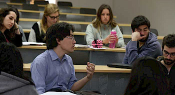Estudiantes de doctorado, antes de la pandemia, debatiendo al interior de una sala de clases en la UC.