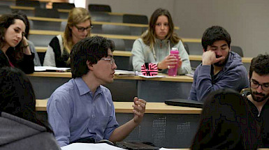 Estudiantes de doctorado, antes de la pandemia, debatiendo al interior de una sala de clases en la UC.