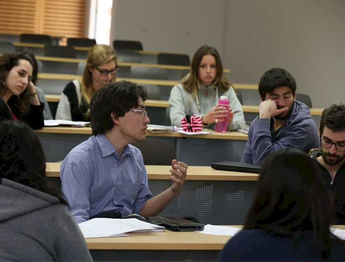 Estudiantes de doctorado, antes de la pandemia, debatiendo al interior de una sala de clases en la UC.