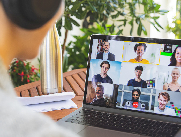 a woman is using a laptop to video chat with other people