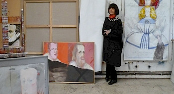Retrato de Claudia Campaña a la fallecida artista Roser Bru, en el año 2009. Posando de pie, ropa negra, brazos cruzados, junto a sus cuadros, en medio de su taller.