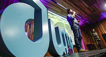Foto de una persona en un escenario frente a unas letras grandes que dicen JUMP
