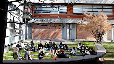 Grupo de alumnos y alumnas sentados en el pasto de la campus San Joaquín.