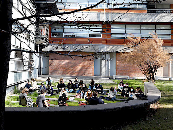 Grupo de alumnos y alumnas sentados en el pasto de la campus San Joaquín.