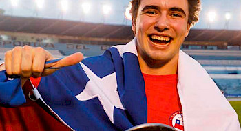 hombre joven sonriendo y con una bandera chilena en los hombros