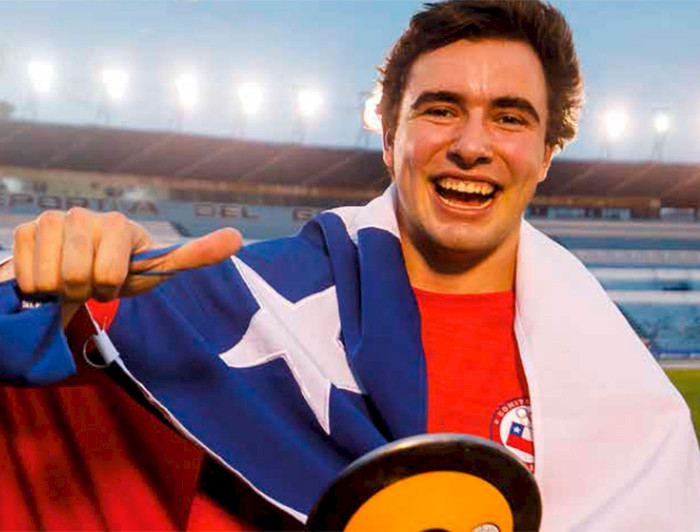 hombre joven sonriendo y con una bandera chilena en los hombros 