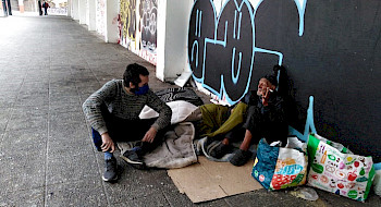 Estudiante de la UC junto a un hombre en situación de calle de la plaza El Pedregal de calle Portugal.