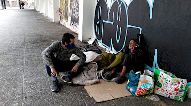 Estudiante de la UC junto a un hombre en situación de calle de la plaza El Pedregal de calle Portugal.