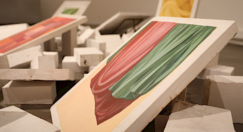Foto de bloques de yeso, esparcidos en el sueldo, con algunos bloques mostrando pinturas de telas en distintos colores y pliegues.