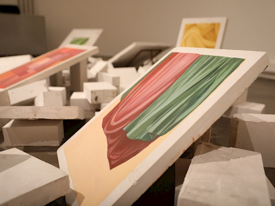 Foto de bloques de yeso, esparcidos en el sueldo, con algunos bloques mostrando pinturas de telas en distintos colores y pliegues.