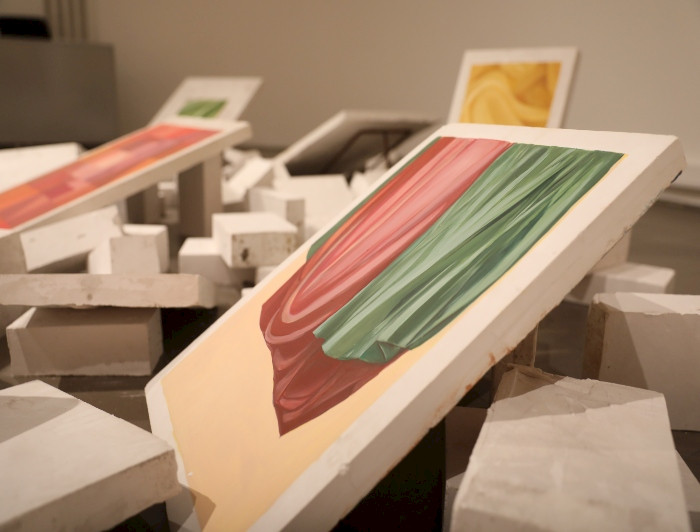 Foto de bloques de yeso, esparcidos en el sueldo, con algunos bloques mostrando pinturas de telas en distintos colores y pliegues.