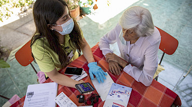 Voluntaria entrega un celular a una persona mayor. Imagen: Karina Fuenzalida.