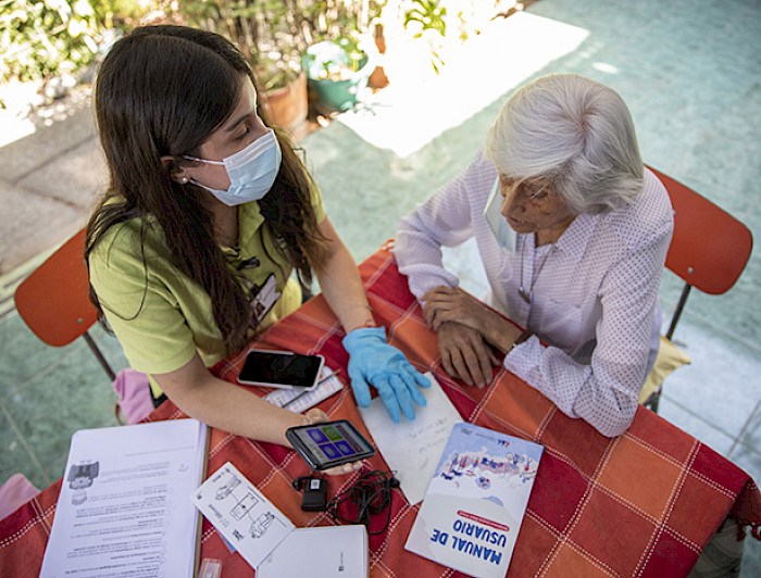 Voluntaria entrega un celular a una persona mayor. Imagen: Karina Fuenzalida.