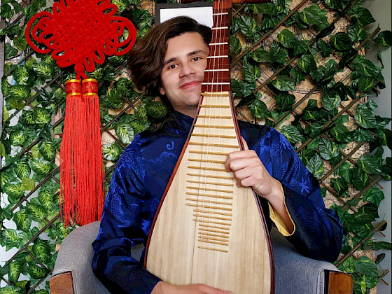 a man in a blue shirt holding a chinese musical instrument