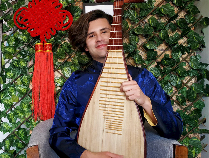 a man in a blue shirt holding a chinese musical instrument