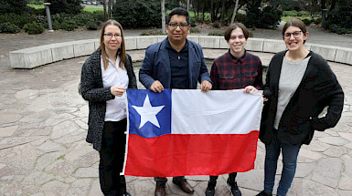 four people holding a chilean flag in front of a building