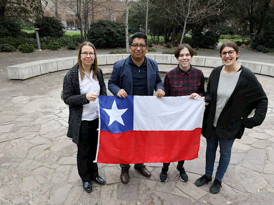 four people holding a chilean flag in front of a building