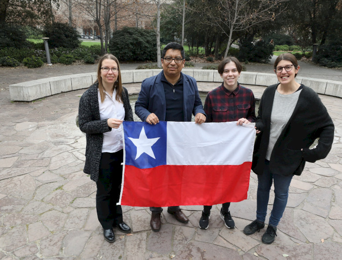 four people holding a chilean flag in front of a building