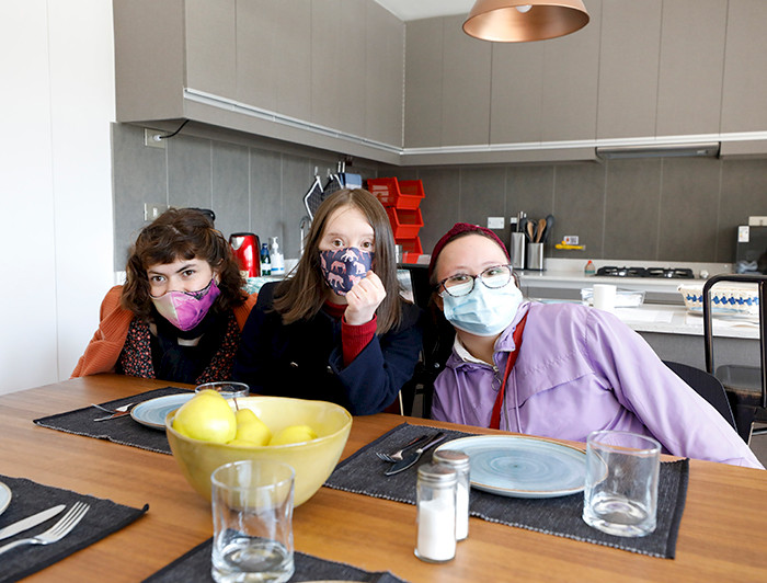 tres mujeres con mascarillas sentadas en sus sillas frente a una mesa de comedor