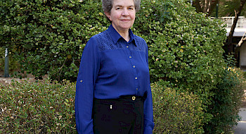 Retrato de profesora Bárbara Loeb frente a unos arbustos en campus San Joaquín.