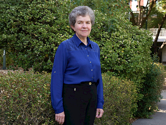 Retrato de profesora Bárbara Loeb frente a unos arbustos en campus San Joaquín.
