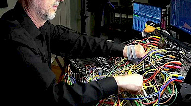 a man working in front of a computer with lots of wires