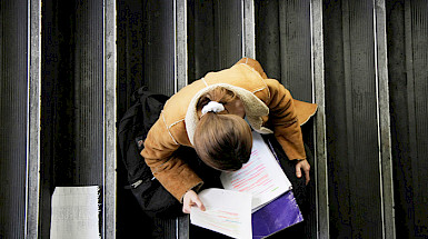 Alumna estudia sobre unas escaleras.