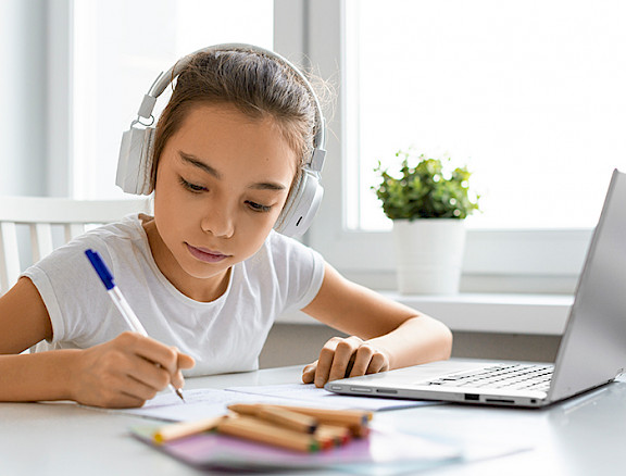 Girl student with headphones in front of a computer.