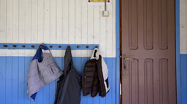 Tres parkas colgando en un perchero junto a la puerta de una escuela.