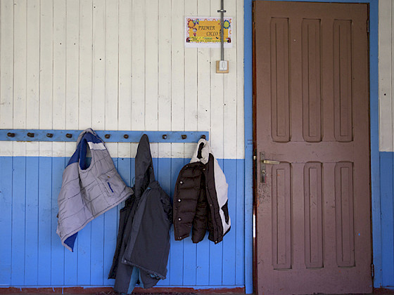 Tres parkas colgando en un perchero junto a la puerta de una escuela.