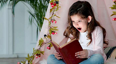 niña leyendo un libro, su rostro expresa alegría