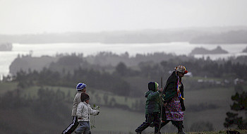 Mujer y niños mapuche caminando por el campo