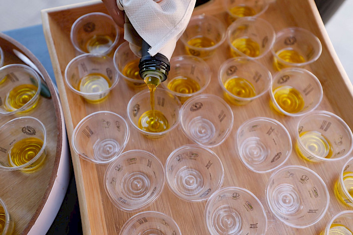 botella llenando pequeños vasos plásticos con aceite de oliva del huasco