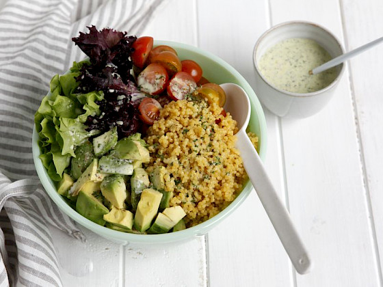 recipiente de cerámica con ensalada de tomate, palta y cuscus.