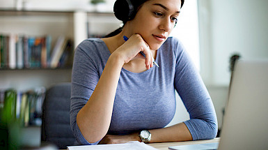female student with headphones watching a computer
