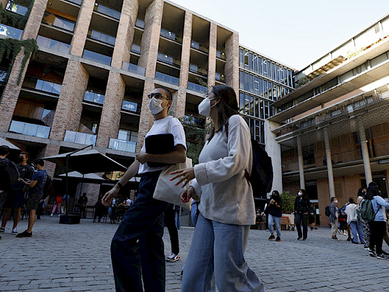 Pareja con mascarilla caminando por el patio de la Facultad de Comunicaciones.