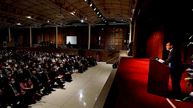 President Ignacio Sanchez giving a speech in front of an audience gathered in the hall.