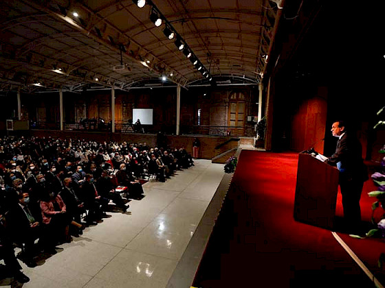 President Ignacio Sanchez giving a speech in front of an audience gathered in the hall.