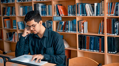 hombre sentado leyendo en una biblioteca