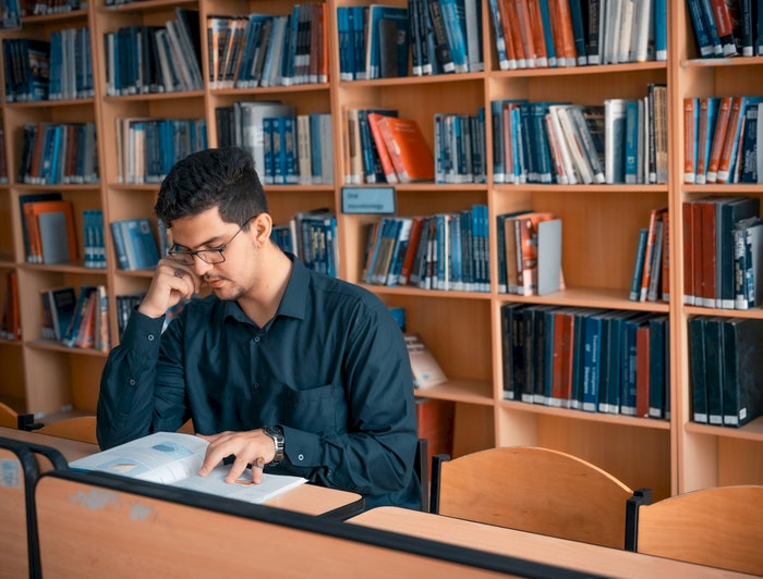 hombre sentado leyendo en una biblioteca